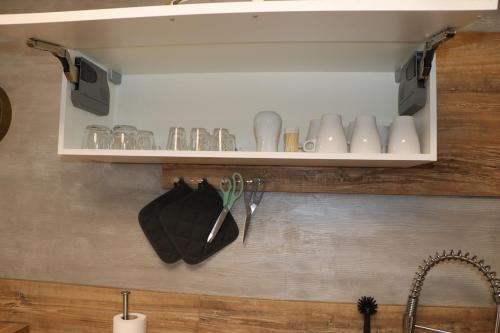 a kitchen shelf with cups and utensils on it at L'Orée du Bois in Longeville-lès-Saint-Avold