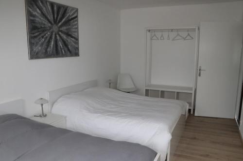 a white bedroom with two beds and a mirror at L'Orée du Bois in Longeville-lès-Saint-Avold