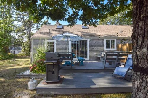 a patio with a grill and a table and umbrella at Peace and Quiet & Spacious Back Deck in Wellfleet