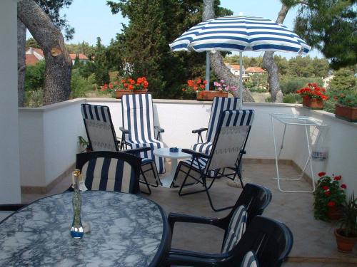 a patio with three chairs and a table and an umbrella at Apartments Dinka in Mirce