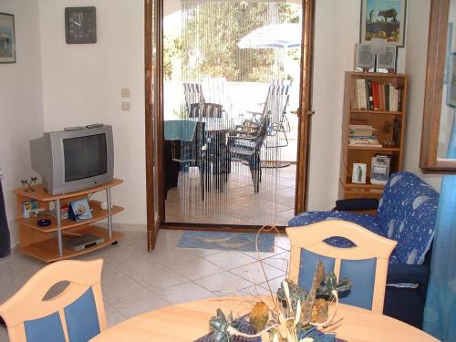 a living room with a tv and a table and chairs at Apartments Dinka in Mirce