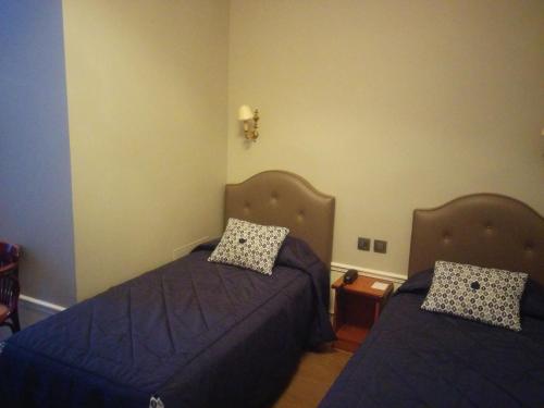 two beds in a room with blue sheets and pillows at Hotel Montpensier in Paris