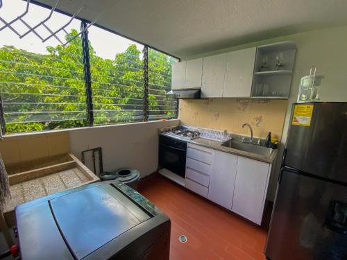 una cucina con mobili bianchi e una grande finestra di Apartamento Sur De Cali Santa Anita Excelente Ubicación a Cali