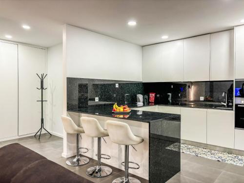 a kitchen with white cabinets and a counter with stools at Bragança Holiday Home new apartment with 2 bedrooms private parking in Bragança