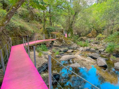 a red bridge over a river with rocks and trees at Casa Trilho the Gaios in Tábua