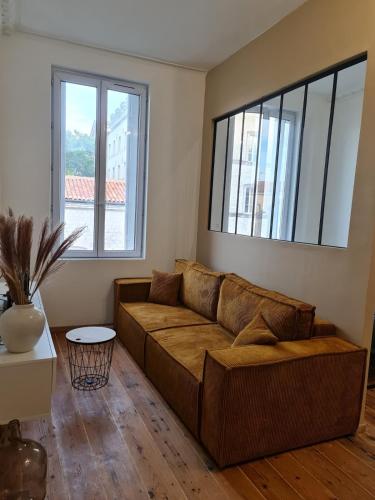 - un salon avec un canapé brun et 2 fenêtres dans l'établissement Jérémy, à Rochefort