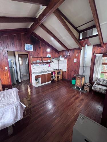 a large living room with wooden floors and a kitchen at Cabañas Gabella in Lago Ranco