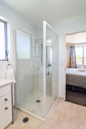 a glass shower in a bathroom with a bed at Comfortable Spacious Home, Close to Beach in Kaikoura