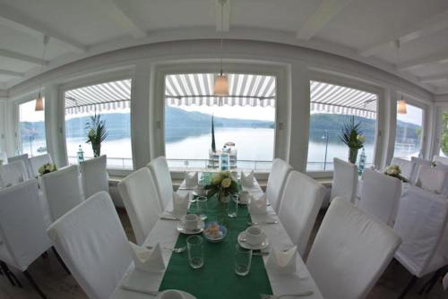 a dining room with a long table and white chairs at Strandhaus Edersee Nr 12 - Kaminzimmer, Seeblick, Badestrand, Seeterrasse in Waldeck