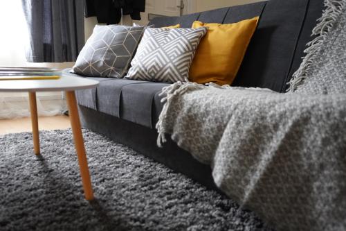 a couch with pillows and a table in a living room at Excellency Stays , Contractors ,families , Comfort Home , Free Parking , in Kent