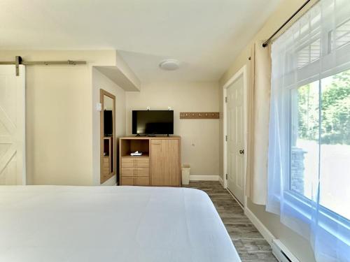 una camera da letto con un letto bianco e una televisione di Bruce Anchor Villa a Tobermory