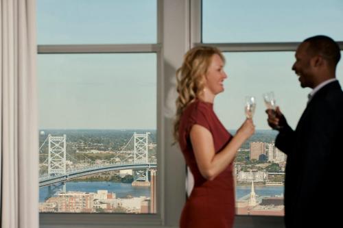 a man and woman drinking wine in front of a window at Loews Philadelphia Hotel in Philadelphia