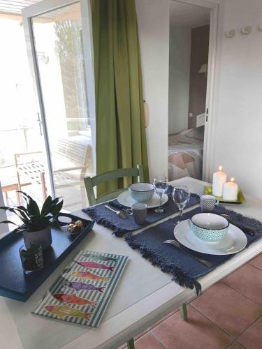 - une table à manger avec un ensemble de assiettes et de verres à vin dans l'établissement Appartement proche mer dans résidence avec piscine, à La Baule