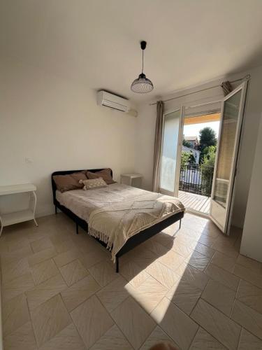 une chambre avec un lit et une grande fenêtre dans l'établissement T2 lumineux avec Terrasse proche du Tram, à Le Crès