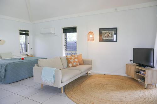 a living room with a couch and a tv and a bed at Makayla Palms in Rarotonga