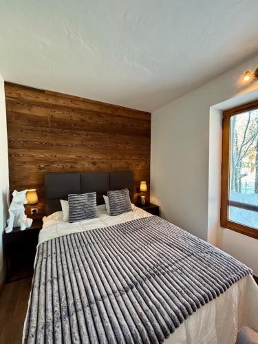 une chambre avec un grand lit avec un mur en bois dans l'établissement Charmant appartement aux portes de Megeve, à Demi-Quartier