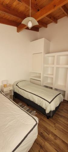 Dos camas en una habitación con paredes blancas y techos de madera. en Elved, en Esquel