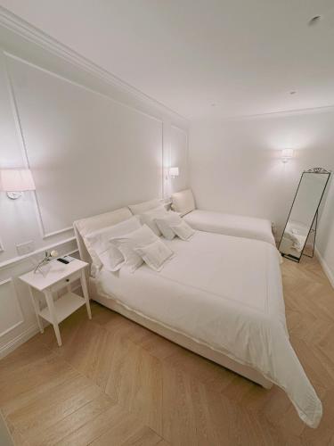 a white bedroom with a large bed and a side table at DIMORA CARDUCCI in Bari