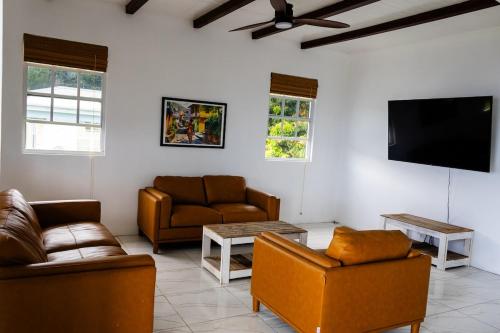 ein Wohnzimmer mit Sofas und einem Flachbildfernseher in der Unterkunft Sea and Summit Villa in Roseau