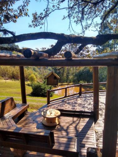 a wooden deck with a table and a tree at Refúgio Serra Grande in Três Coroas