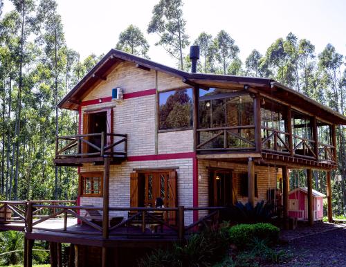 a house in the woods with a wrap around porch at Refúgio Serra Grande in Três Coroas