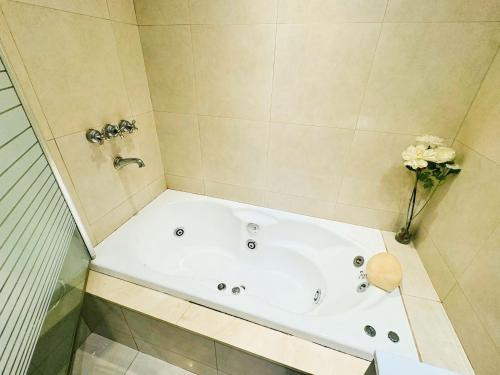 a bathroom with a bath tub with a vase of flowers at Buenos Ayres Apartment in Buenos Aires