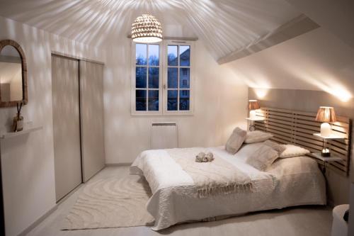 a white bedroom with a large bed and a window at Muraille du château avec jacuzzi in Nemours