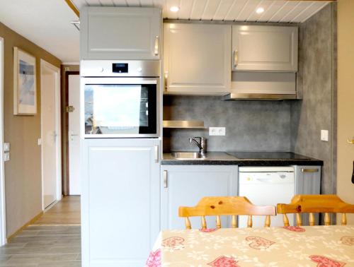 une cuisine avec des armoires blanches et une table et des chaises dans l'établissement Résidence Palafour - Studio profitant d'une vue sur la grande motte MAE-8154, à Tignes