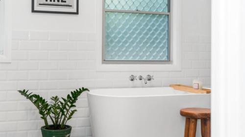 a bathtub in a bathroom with a potted plant at Brunswick Beach Shack in Brunswick Heads