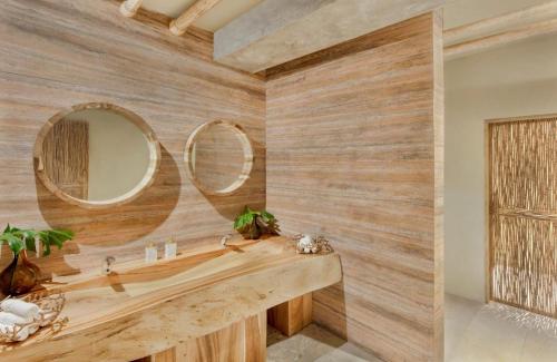 a bathroom with two mirrors and a wooden wall at Oceanfront Living & Surfing in Cabo Paradisiacal 2BR Condo in San José del Cabo