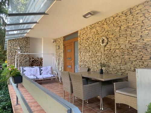 a patio with a table and chairs and a stone wall at Baladise Apartman in Balatonvilágos