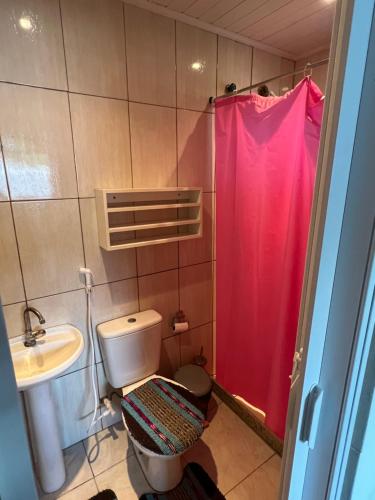 a bathroom with a toilet and a pink shower curtain at Casa de praia seca in Araruama