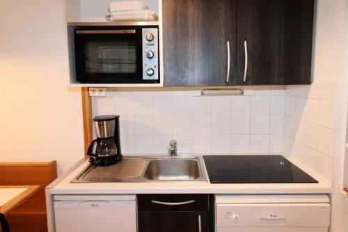 une cuisine avec un évier et un micro-ondes dans l'établissement Résidence Hameau Du Borsat 3 - Appartement confortable · Ski au pied MAE-3684, à Tignes