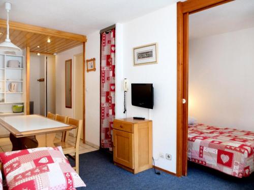 Cette chambre comprend un lit, une table et une télévision. dans l'établissement Résidence Hameau Du Borsat 3 - Appartement confortable · Ski au pied MAE-3684, à Tignes