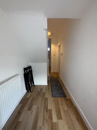 a hallway with white walls and a wooden floor at Charming 3-Bedroom house in Cardiff