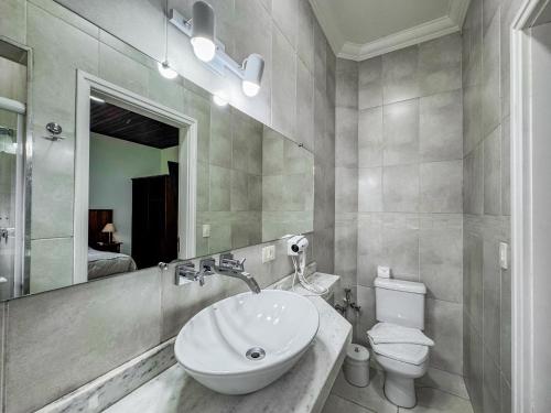 a bathroom with a sink and a toilet and a mirror at Pousada Victoria Villa By Nacional Inn - A 800 metros da Vila Capivari in Campos do Jordão