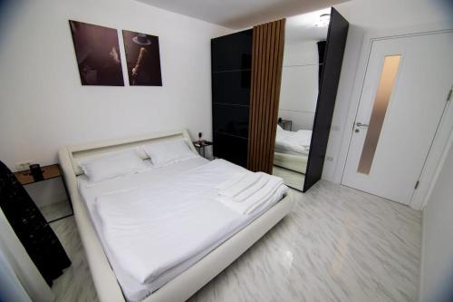 un letto bianco in una stanza con specchio di Central Lux 2 camere-parcare gratuita, check-in cifru a Piteşti