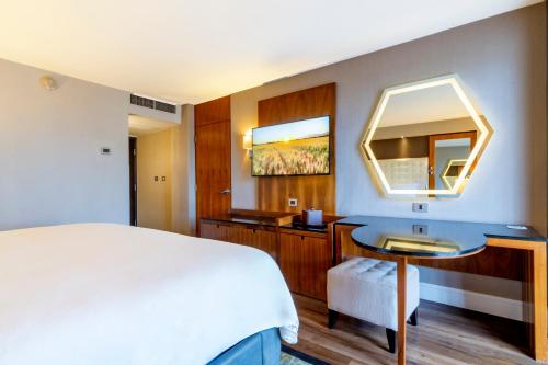 a bedroom with a bed and a desk and a mirror at Hotel Lucerna Tijuana in Tijuana