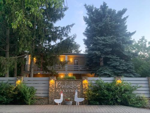 a house with a garden with two chairs and lights at Baladise Apartman in Balatonvilágos
