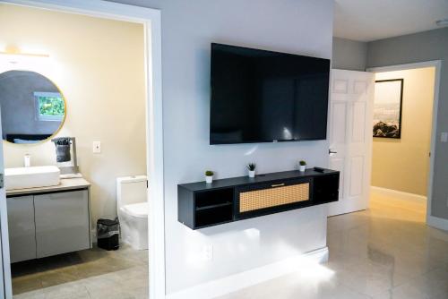 a bathroom with a sink and a tv on a wall at Grand Home Jacuzzi, Heated Pool, Games, BB Court L20 in Miami