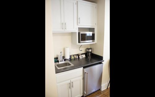 a kitchen with white cabinets and a sink and a microwave at Leland House Suites of Durango in Durango