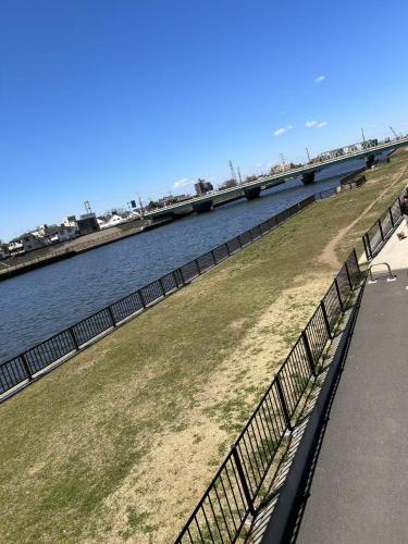 a fence next to a body of water with a bridge at Sunflower 民泊 in Tokyo