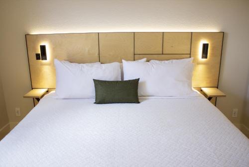 a large bed with white pillows and a green pillow at Leland House Suites of Durango in Durango