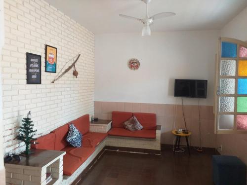 Una sala de estar con un sofá rojo y un televisor. en Casa Praia Grande, en Nova Almeida