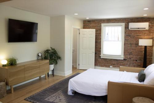 a bedroom with a white bed and a brick wall at Leland House Suites of Durango in Durango