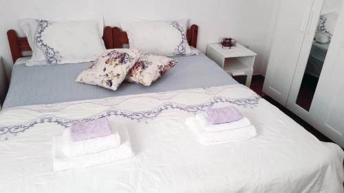 a white bed with purple and white pillows on it at Medieval Rose Guest House in Rhodes Town