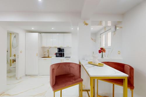 a white kitchen with a table and two chairs at Suite romantique avec jacuzzi in Pontault-Combault
