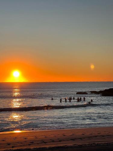 a group of people in the ocean at sunset at Harbourfront 3 Bed 2 Bath Opposite Manly Wharf With Harbour Views in Sydney