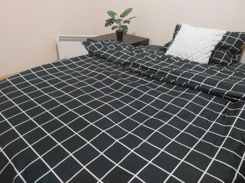 a bed with black and white sheets and pillows at Sorin Apartments Gevgelija in Gevgelija