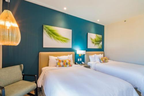 two beds in a room with blue walls and a chair at Torre Lucerna Hotel Ensenada in Ensenada